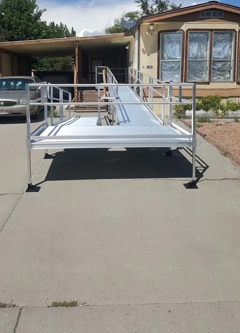 Aluminum wheelchair ramp with a landing and handrails at a home's entry