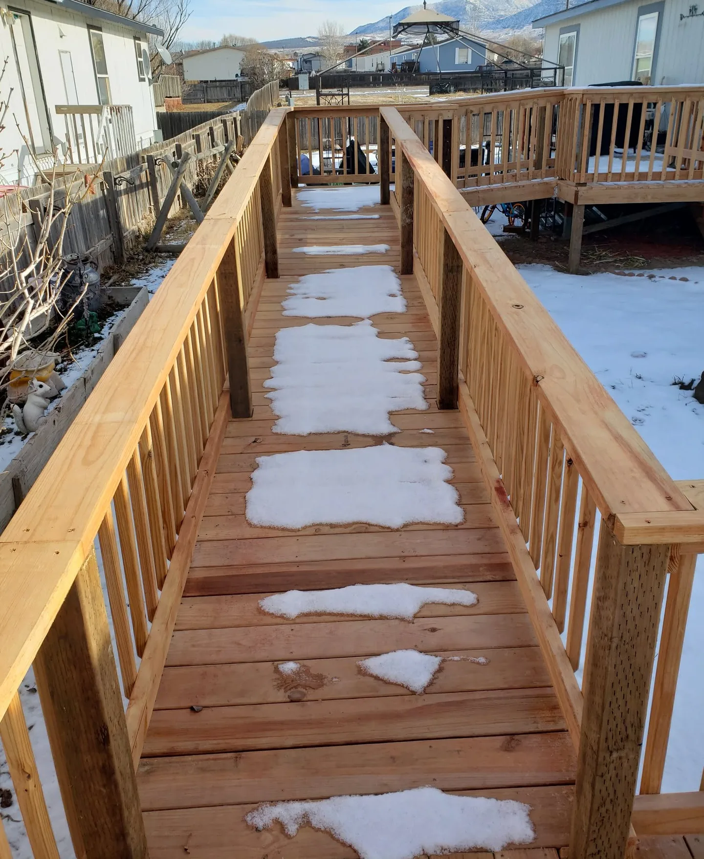 Long wooden wheelchair ramp with railings on both sides, leading to a deck