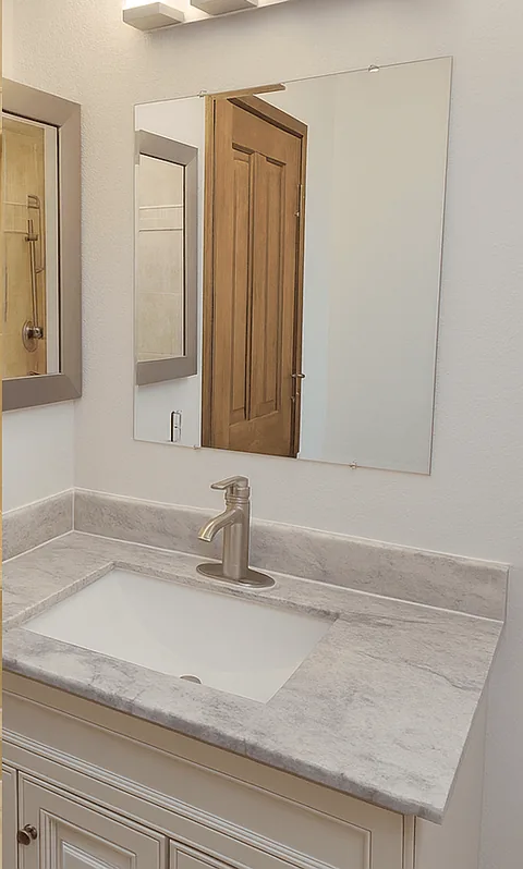 Remodeled bathroom vanity with a marble-look top and brushed nickel faucet